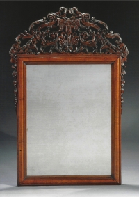 Een spiegel in een notenhouten lijst, bekroond met ajour snijwerk